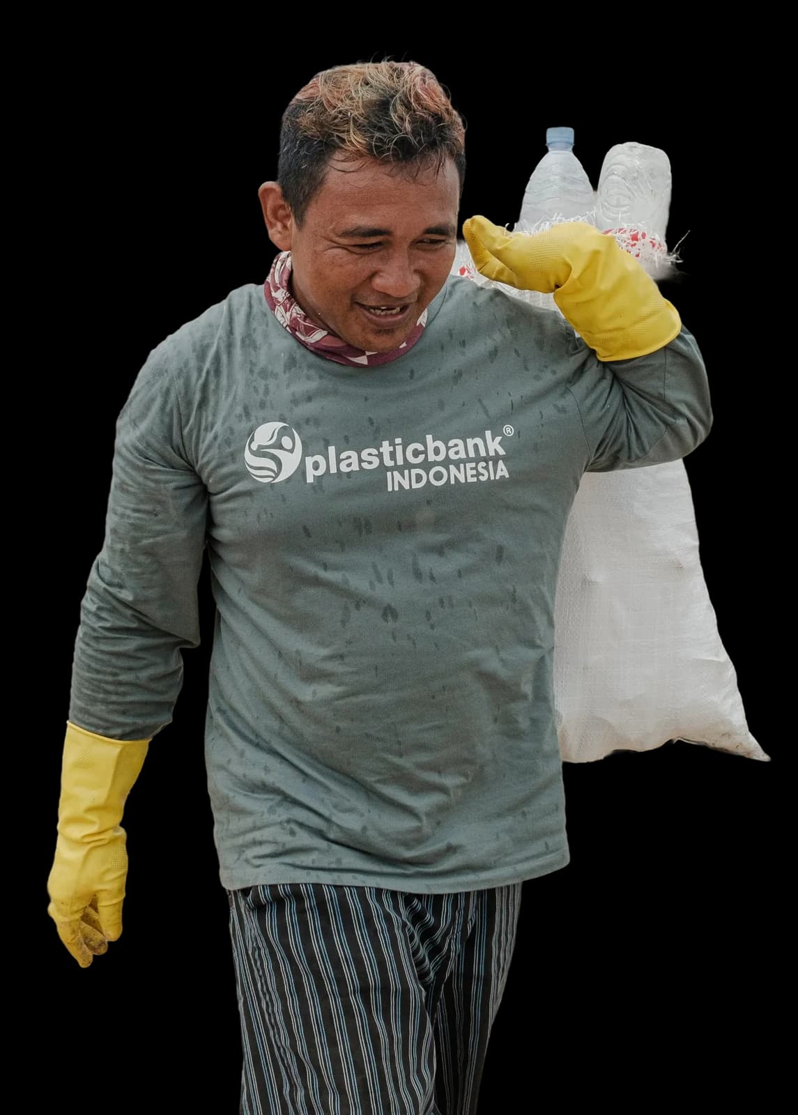 Juhari, a Plastic Bank collection member in Bali, carrying gathered plastic on the beach